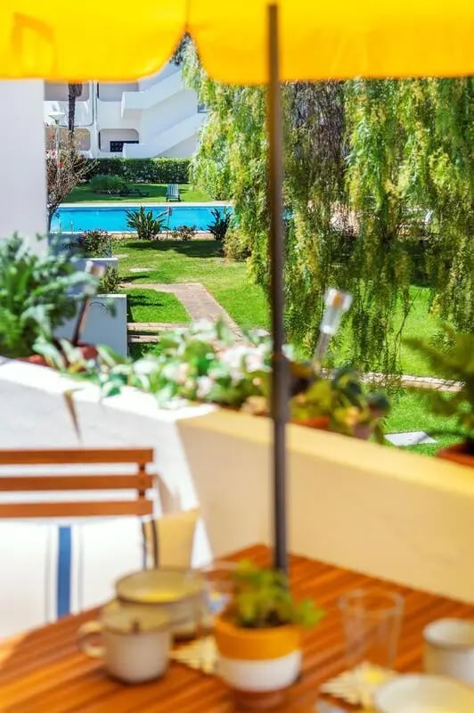 Table umbrella pool and green lawn exterior at Luxurious 1-bedroom apartment in Vilamoura in Faro Student Accommodation