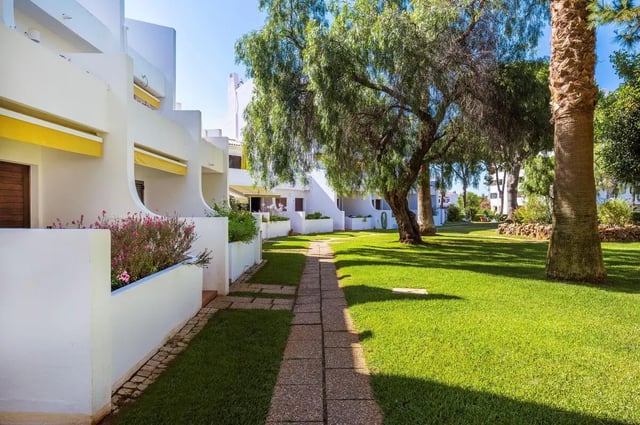 White buildings with yellow awnings and lawn exterior at Luxurious 1-bedroom apartment in Vilamoura in Faro Student Accommodation