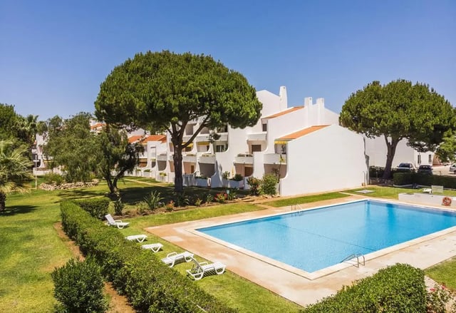 White buildings with balconies near pool and trees exterior at Luxurious 1-bedroom apartment in Vilamoura in Faro Student Accommodation