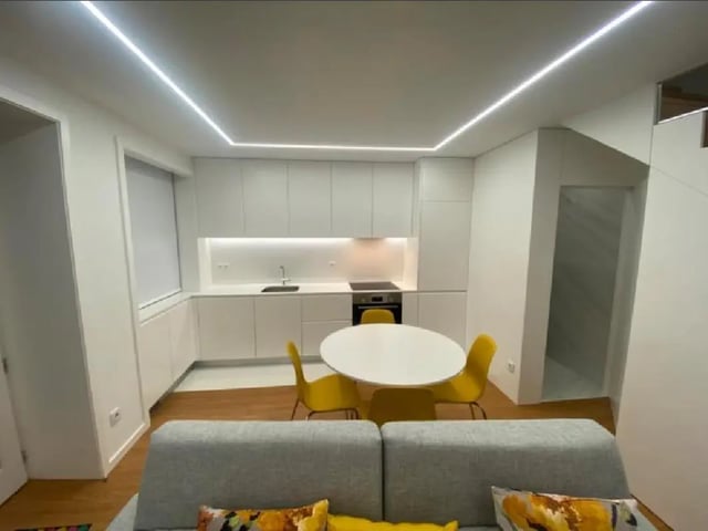 Modern kitchen with white cabinets dining table and yellow chairs kitchen at Luxury 1 Bedroom Apartment close to  Polytechnic Institute of Viana do Castelo in Viana Do Castelo Student Accommodation