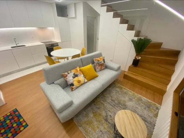 Gray sofa with pillows kitchen and stairs living room at Luxury 1 Bedroom Apartment close to  Polytechnic Institute of Viana do Castelo in Viana Do Castelo Student Accommodation