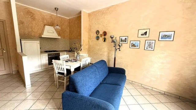 Blue sofa dining table kitchen area living room at Tasteful 1-bedroom apartment in Albenga in Albenga Student Accommodation