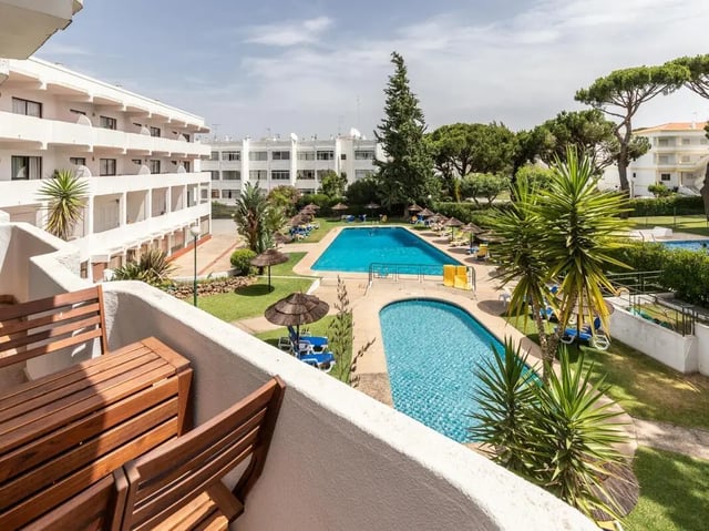 Wooden table chairs pools with umbrellas exterior at Nice 1-bedroom flat in Faro in Faro Student Accommodation
