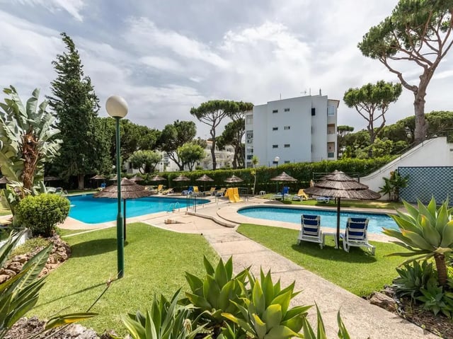 Pool umbrellas lounge chairs and building exterior at Nice 1-bedroom flat in Faro in Faro Student Accommodation