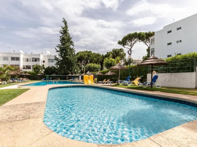 Pool lounge chairs umbrellas and slide outdoor swimming area at Nice 1-bedroom flat in Faro in Faro Student Accommodation