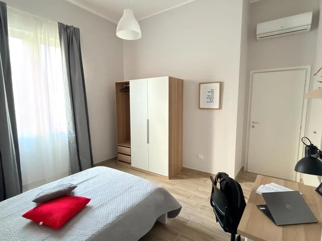 Bed dresser desk lamp laptop backpack bedroom study area at Amazing single room in Pescara in Pescara Student Accommodation
