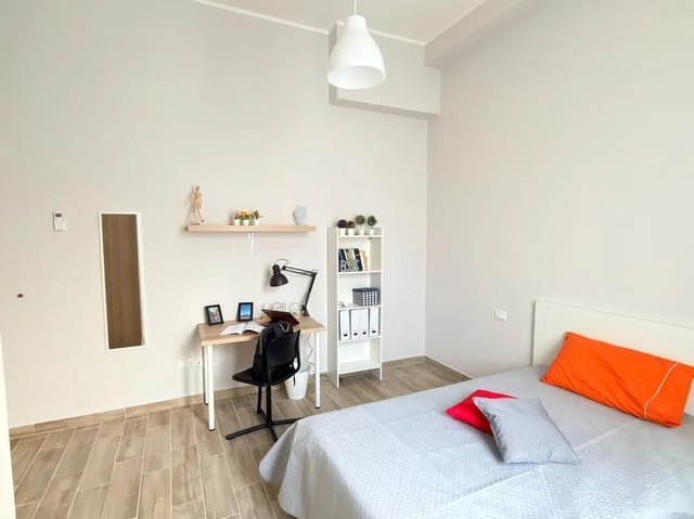 Desk lamp bookshelf bed and pillows bedroom at Amazing single room in Pescara in Pescara Student Accommodation