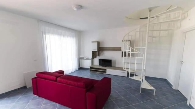 Red sofa television white spiral staircase living room at Comfy Apartment close to the beach in Agrigento Student Accommodation
