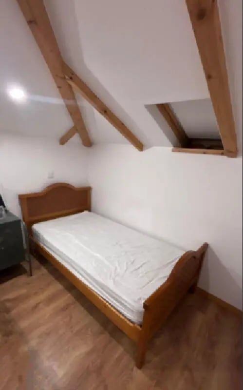 Wooden bed and mattress under sloping ceiling Bedroom at Cozy Single Bedroom – Exclusively for IPVC Students, near Viana do Castelo Train Station in Viana Do Castelo Student Accommodation