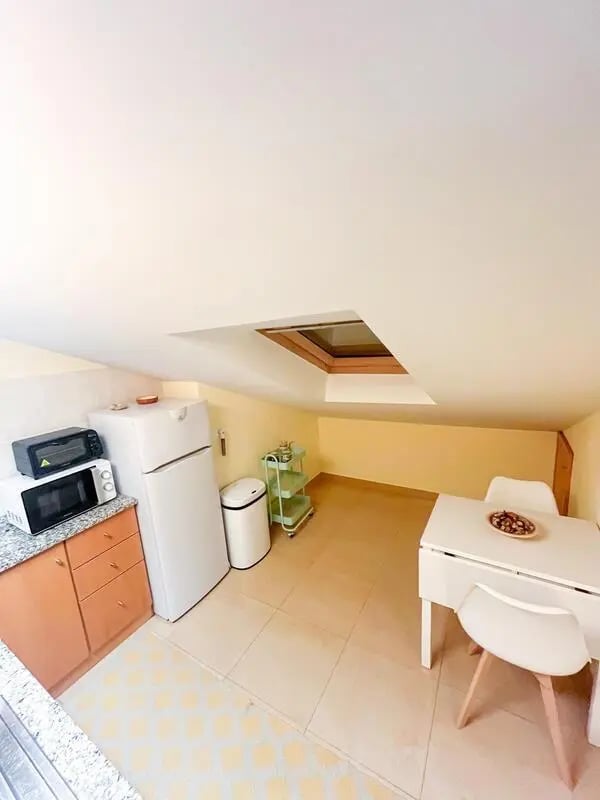 Kitchenette with fridge microwave table and chairs kitchen at Beachfront Loft in Viana Do Castelo Student Accommodation