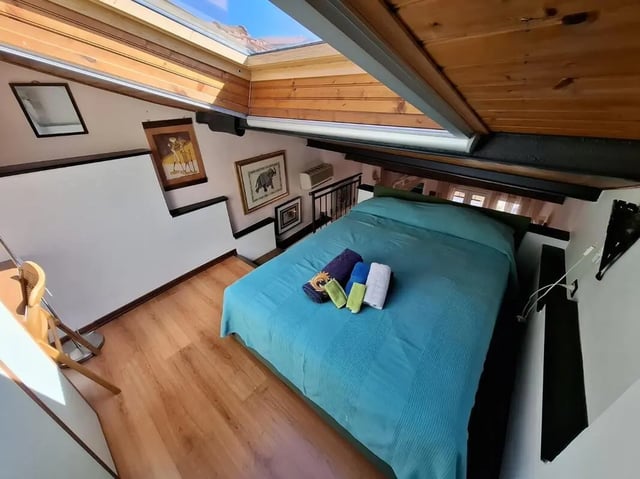 Bed with towels wooden floor artwork skylight bedroom at Apartment with Terrace in Imperia in Imperia Student Accommodation