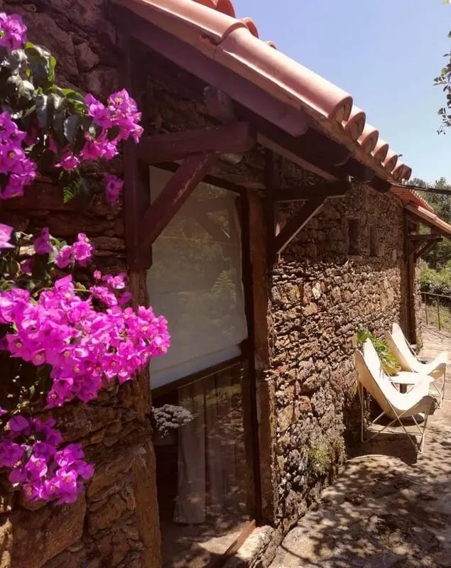 Stone cottage with pink flowers and chairs exterior at Charming and serene country house in Sopo, Vila Nova de Cerveira in Viana Do Castelo Student Accommodation