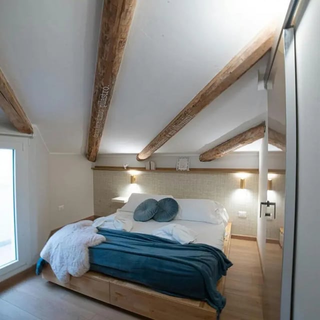 Wooden beams bed with blue blanket white Bedroom at Inviting 1-bedroom apartment near Pescara Centrale in Pescara Student Accommodation