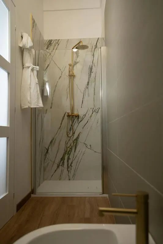 Marble shower with gold fixtures and robes bathroom at 1-Bedroom apartment near the Pescara Centrale in Pescara Student Accommodation