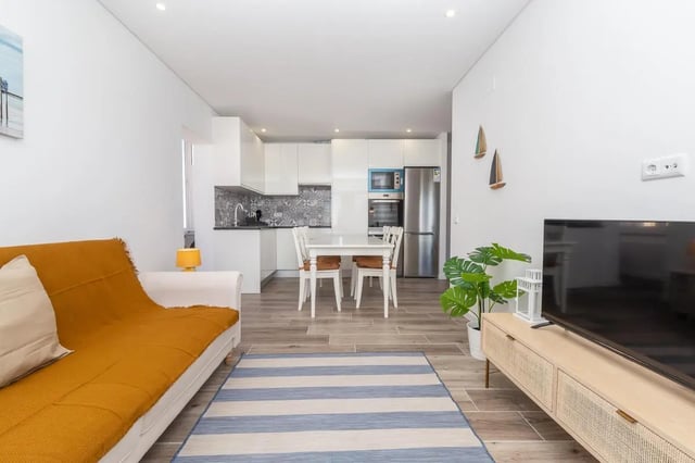 Sofa dining table and kitchen area living room at Neat 2-bedroom flat in Olhão in Faro Student Accommodation