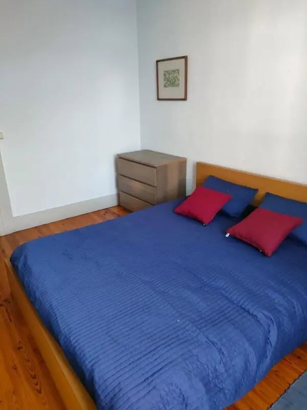 Bed with blue quilt red pillows dresser artwork bedroom at Nice double bedroom in Ponte de Lima in Viana Do Castelo Student Accommodation