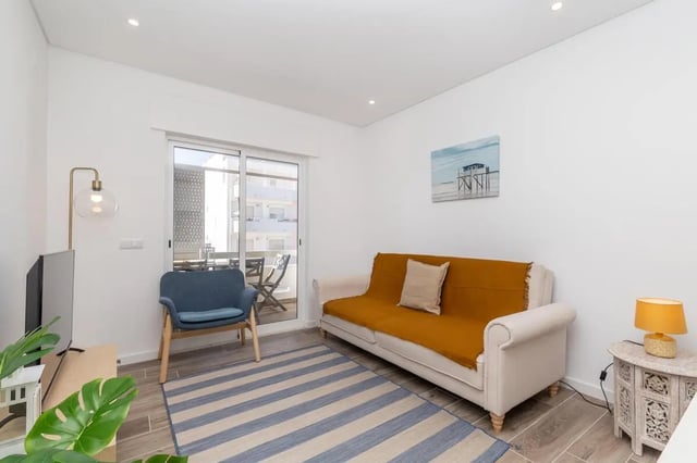 Sofa armchair floor lamp rug beach artwork living room at Neat 2-bedroom flat in Olhão in Faro Student Accommodation