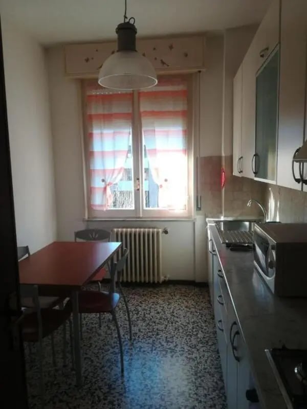 Dining table chairs radiator kitchen counter kitchen at Comfy 2 bedroom apartment close to Palazzo Ducale in Parma Student Accommodation