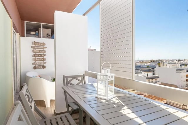 Table chairs lantern beach signs balcony exterior at Neat 2-bedroom flat in Olhão in Faro Student Accommodation