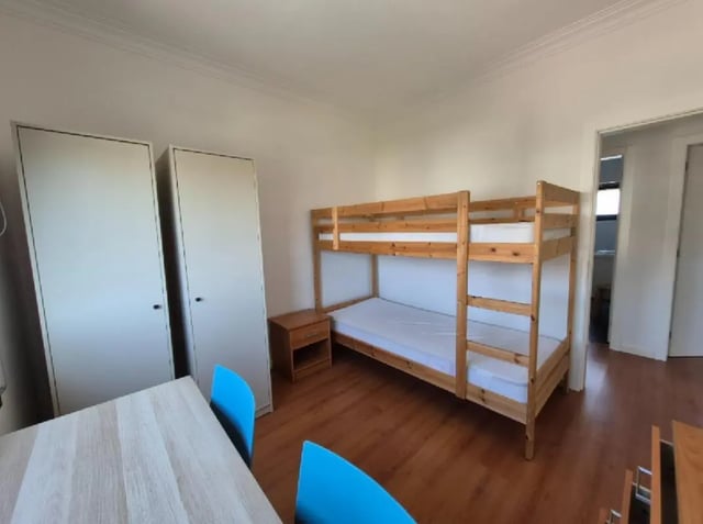 Bunk beds two wardrobes table blue chairs bedroom at Nice Twin Bedroom close to City Park of Viana do Castelo in Viana Do Castelo Student Accommodation