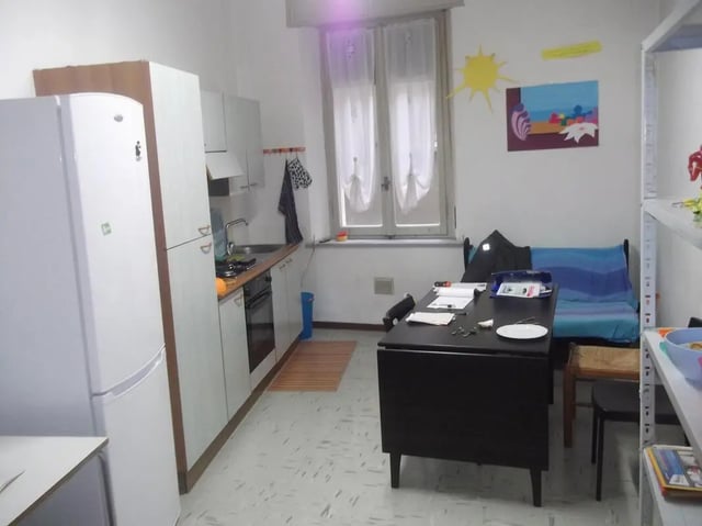 Kitchen area with fridge stove sink couch and desk kitchen at Single Bedroom in a 4 bedroom apartment in Parma in Parma Student Accommodation