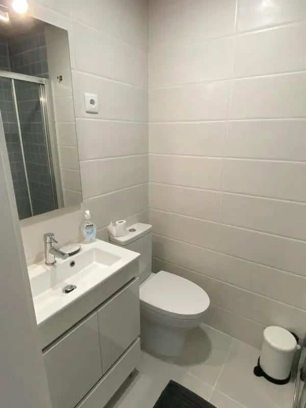 Sink toilet shower and trash can bathroom at Welcoming Studio close to Viana do Castelo Center/Train Station in Viana Do Castelo Student Accommodation