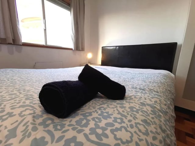 Bed with patterned duvet and black towels bedroom at Double Bedroom close to Minho University 7 in Guimaraes Student Accommodation