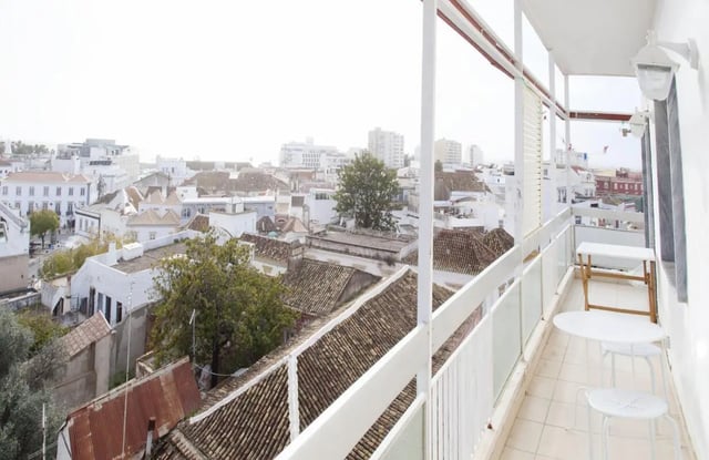Balcony with tables and chairs balcony overlooking rooftops at Sunny and lovely 1-bedroom flat in Faro Student Accommodation