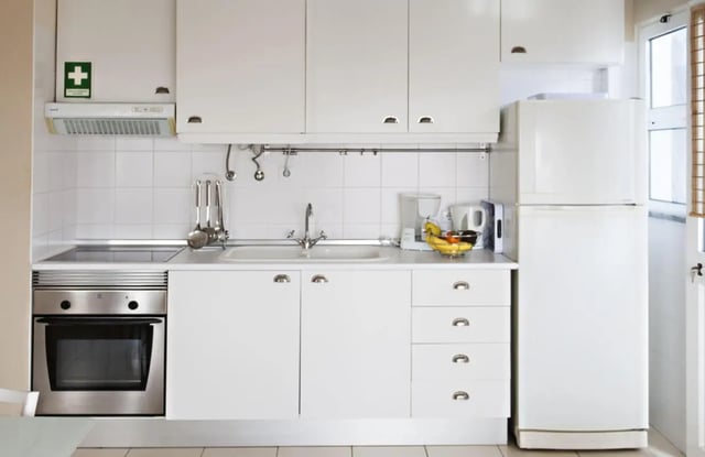 White cabinets fridge oven sink kitchen utensils kitchen at Sunny and lovely 1-bedroom flat in Faro Student Accommodation