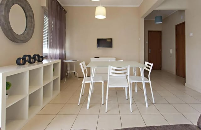 White shelving unit dining table four chairs living room at Sunny and lovely 1-bedroom flat in Faro Student Accommodation