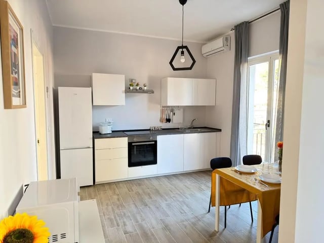 Modern kitchen with white cabinets microwave fridge and dining table kitchen at Amazing bedroom in Pescara in Pescara Student Accommodation