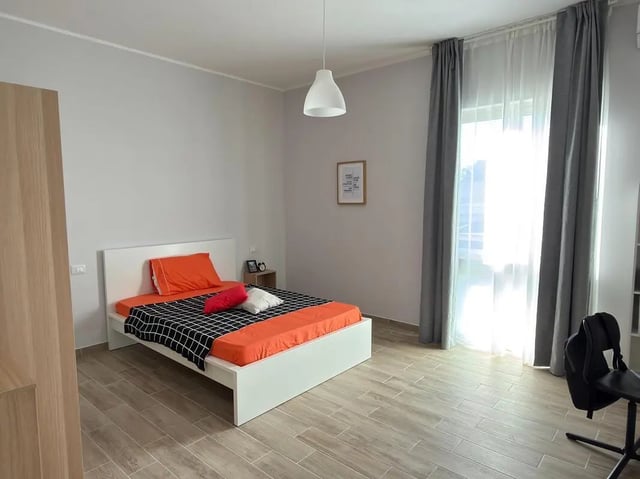 Bed with orange pillows and desk with backpack Bedroom at Amazing bedroom in Pescara in Pescara Student Accommodation