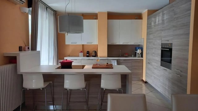 Modern kitchen with island white stools and oven Kitchen at Comfy 3 bedroom apartment close to University of Parma in Parma Student Accommodation
