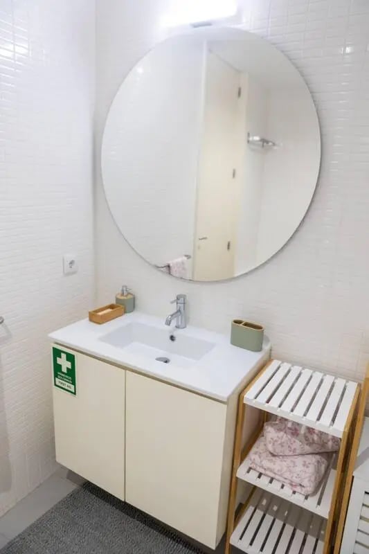 White vanity sink round mirror towels shelf bathroom at Elegant and functional studio in the historic center of Guimarães in Guimaraes Student Accommodation