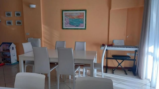 Dining table and chairs keyboard living room at Comfy 3 bedroom apartment close to University of Parma in Parma Student Accommodation