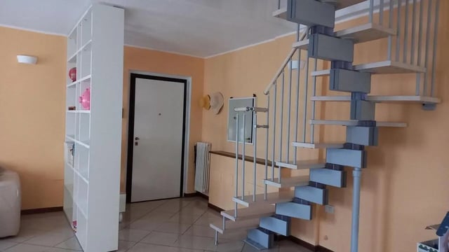 White bookshelf spiral staircase entryway living room at Comfy 3 bedroom apartment close to University of Parma in Parma Student Accommodation