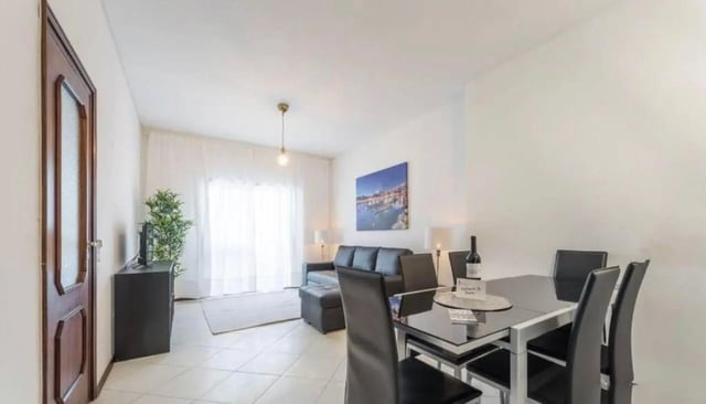 Black sofa dining table and chairs living room at Excellent 3-bedroom apartment next to General Torres metro station in Vila Nova De Gaia Student Accommodation