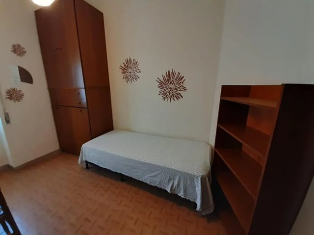 Bed wardrobe bookshelf with floral wall decorations bedroom at Single bedroom close to Università degli Studi Mediterranea di Reggio Calabria in Reggio Calabria Student Accommodation