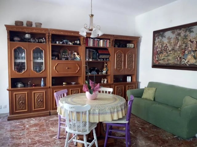 Wooden cabinet dining table green sofa living room at Comfy single bedroom near Università degli Studi Mediterranea di Reggio Calabria in Reggio Calabria Student Accommodation