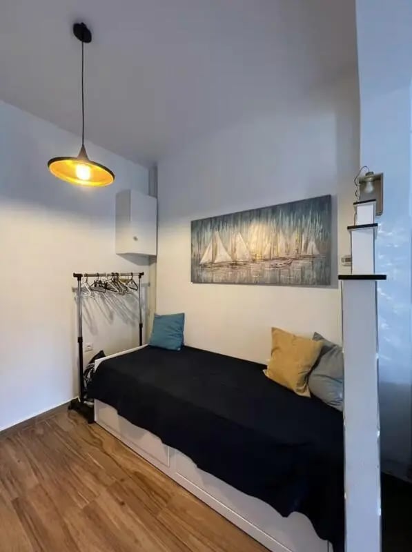 Bed with navy bedding clothes rack painting bedroom at Homely Double Bedroom with a balcony close to Aristotelous Square in Thessaloniki Student Accommodation