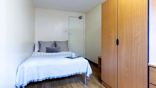 Bed pillows white comforter wooden wardrobe bedroom at Ben Russell Court in Leicester Student Accommodation