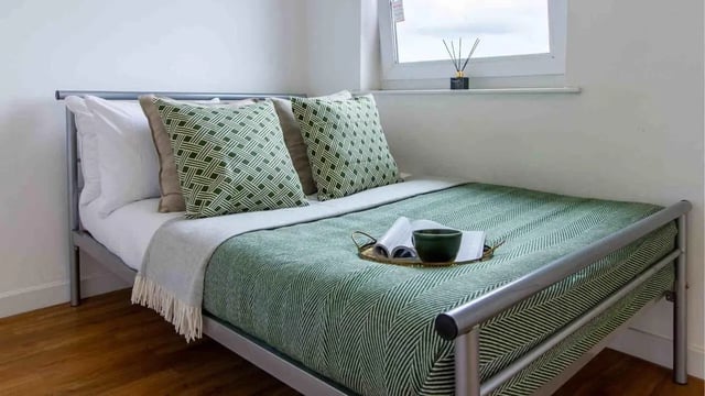 Metal frame bed with green patterned bedding bedroom at Canalside in Birmingham Student Accommodation