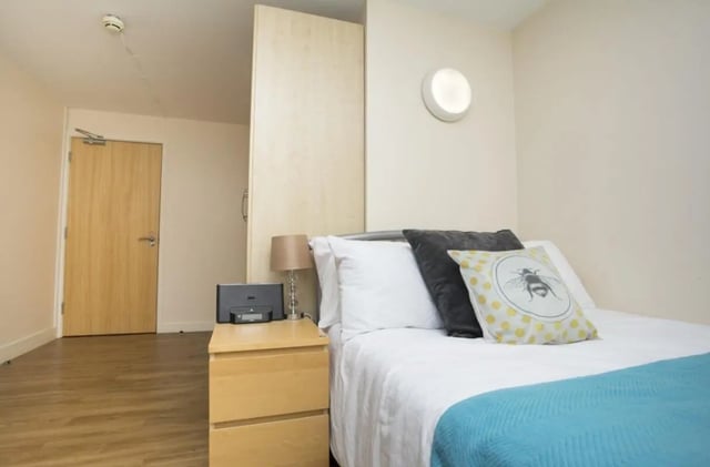 Bed nightstand lamp speakers and bee pillow bedroom at Daisybank Villas in Manchester Student Accommodation