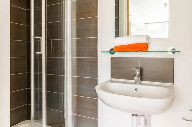 Shower cubicle sink and folded towels bathroom at Portobello Garrow House in London Student Accommodation