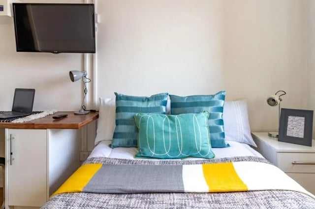 Bed with pillows desk laptop TV bedroom at Portobello Garrow House in London Student Accommodation