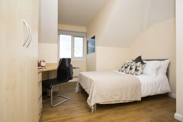 Bed desk chair wardrobe alarm clock television bedroom at Heald Court in Manchester Student Accommodation