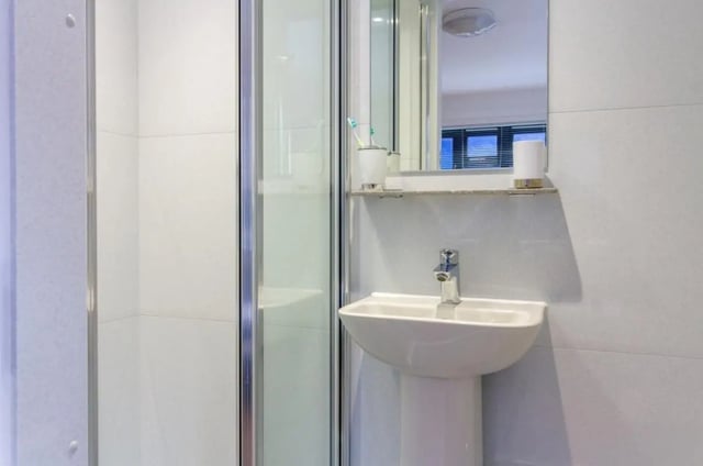 Shower cubicle pedestal sink and mirror bathroom at Surrey Quays Landale House in London Student Accommodation