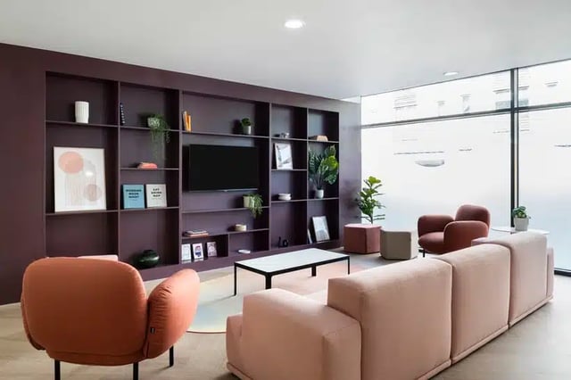 Pink sofas bookshelf with TV and chairs living room at AXO Kingston in Kingston Upon Thames Student Accommodation