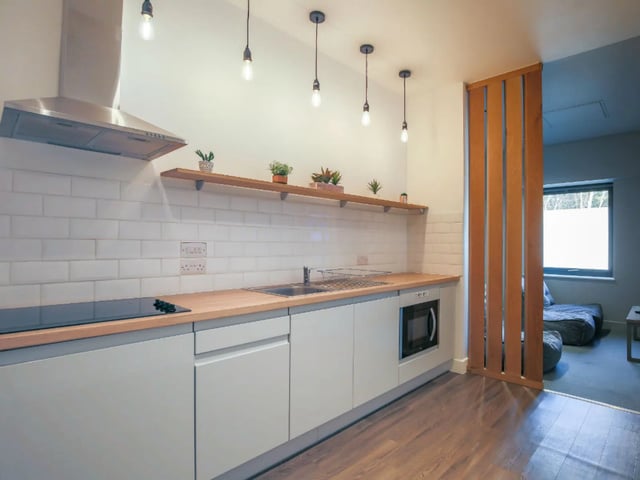 Modern kitchen with light grey cabinets and wooden countertop kitchen at AXO Kingston in Kingston Upon Thames Student Accommodation