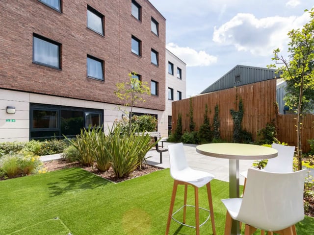 Outdoor patio with table chairs and lawn exterior at AXO Kingston in Kingston Upon Thames Student Accommodation